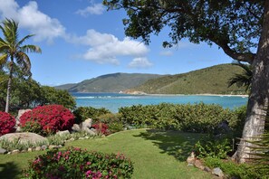 A landscaped garden with a view of a coastal area, including a beach and hills.