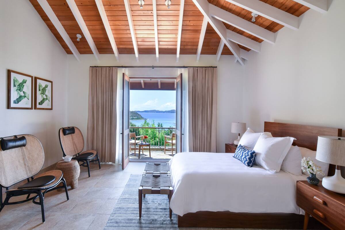 Une chambre d’hôtel avec un lit, une table de chevet, une lampe et une vue sur l’extérieur.