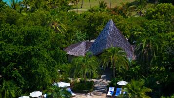 Vue aérienne d’un complexe hôtelier doté d’une piscine, d’une plage et d’une végétation luxuriante.