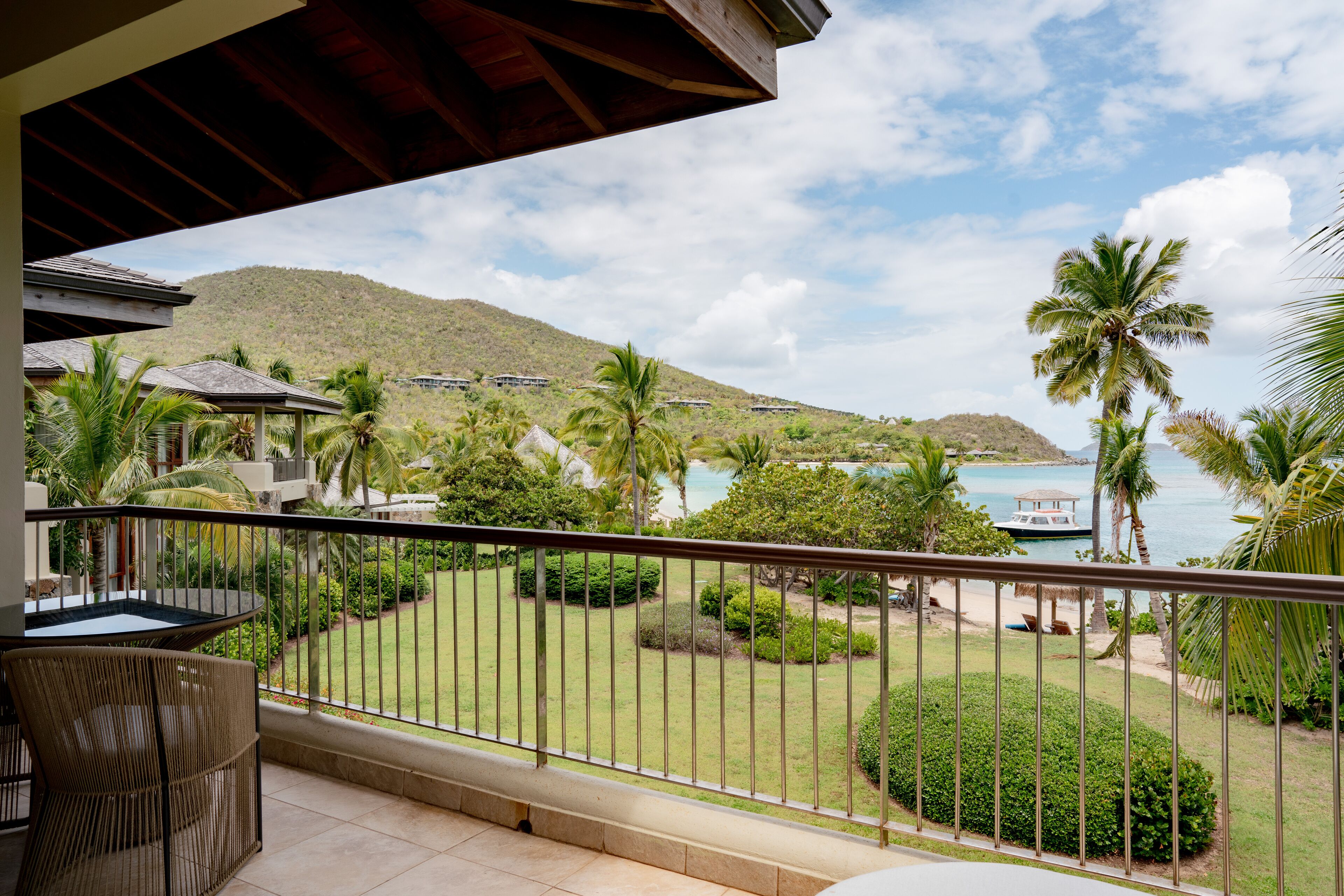 Un balcón con vista a una playa, palmeras y un paisaje montañoso.