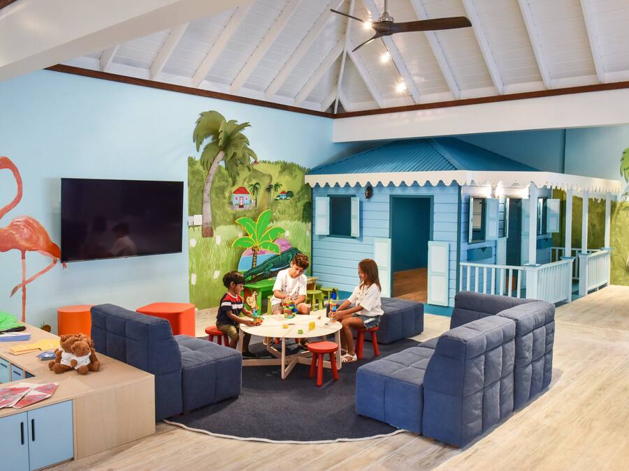 A children's playroom with a mural, seating, and a TV.