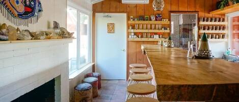 Cocina rústica con techo de madera, chimenea blanca y una barra con taburetes.