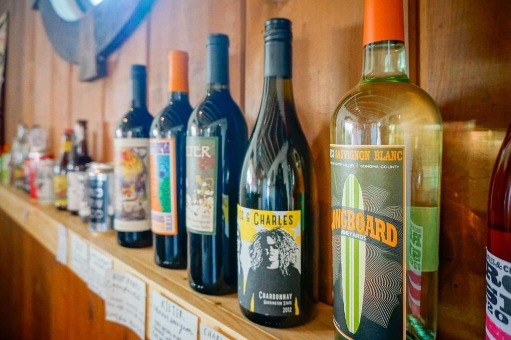 Una fila de botellas de vino sobre una estantería de madera.
