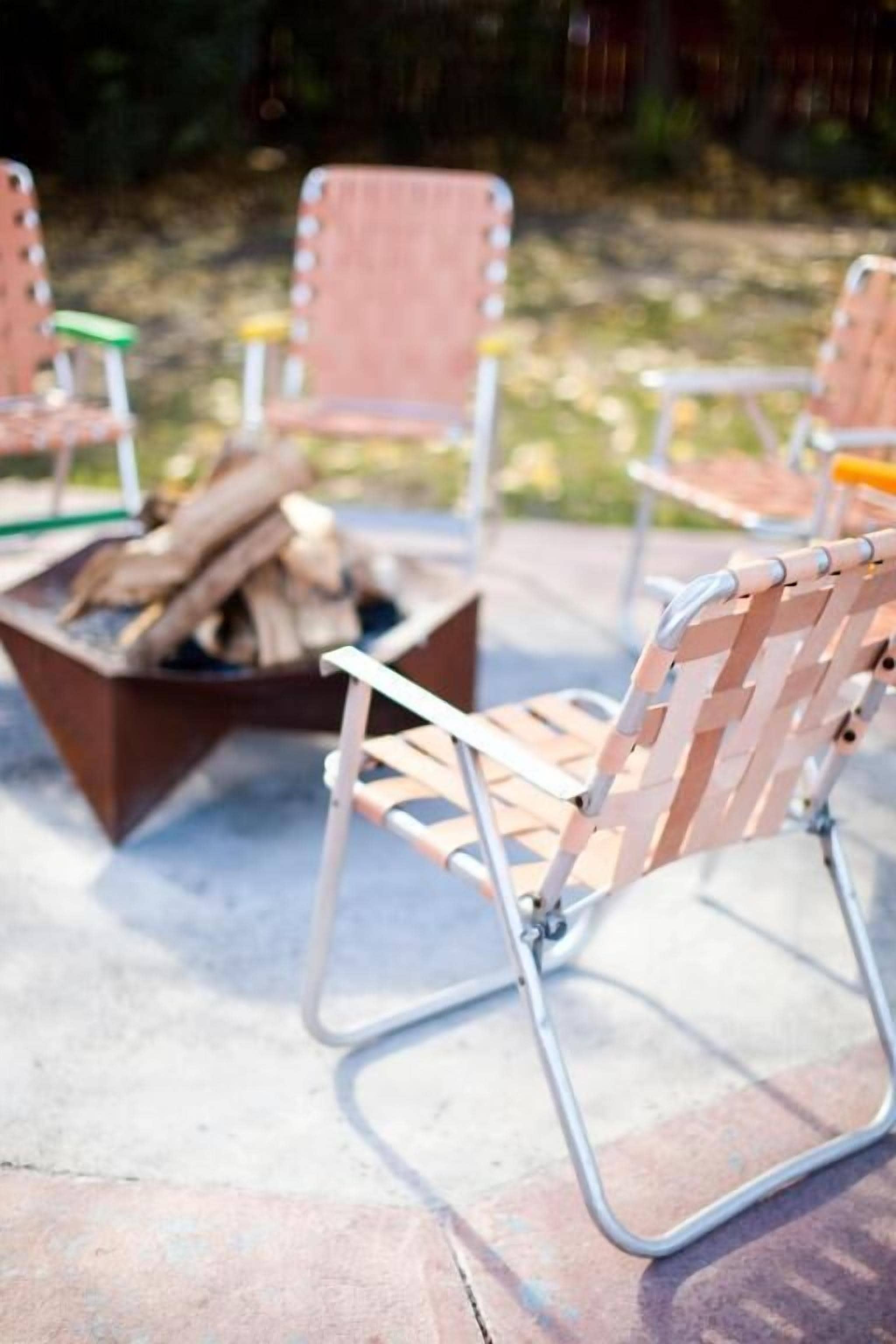 A patio area with metal chairs and a fire pit.