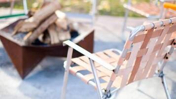 A patio area with metal chairs and a fire pit.
