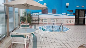 A pool area with a hot tub, lounge chairs, and a table with an umbrella. - Comfort Inn Anderson South (Anderson)