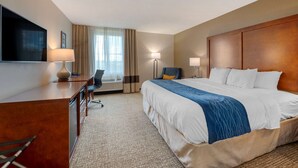 A hotel room with a bed, desk, chair, TV, and lamps. - Comfort Inn Anderson South (Anderson)