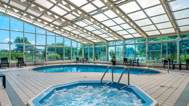 A covered swimming pool with a hot tub, seating area, and a view of the surrounding greenery. - Comfort Inn Anderson South (Anderson)