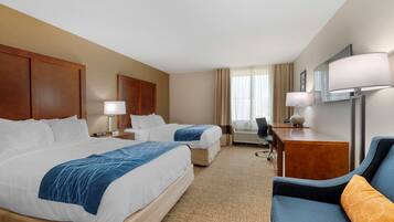 A hotel room with two beds, a desk, a chair, and a TV.