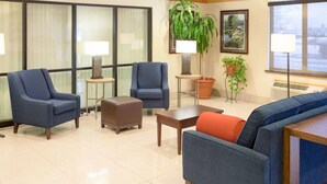 A hotel lobby with a blue sofa, two armchairs, a small table, and a potted plant. - Comfort Inn Anderson South (Anderson)