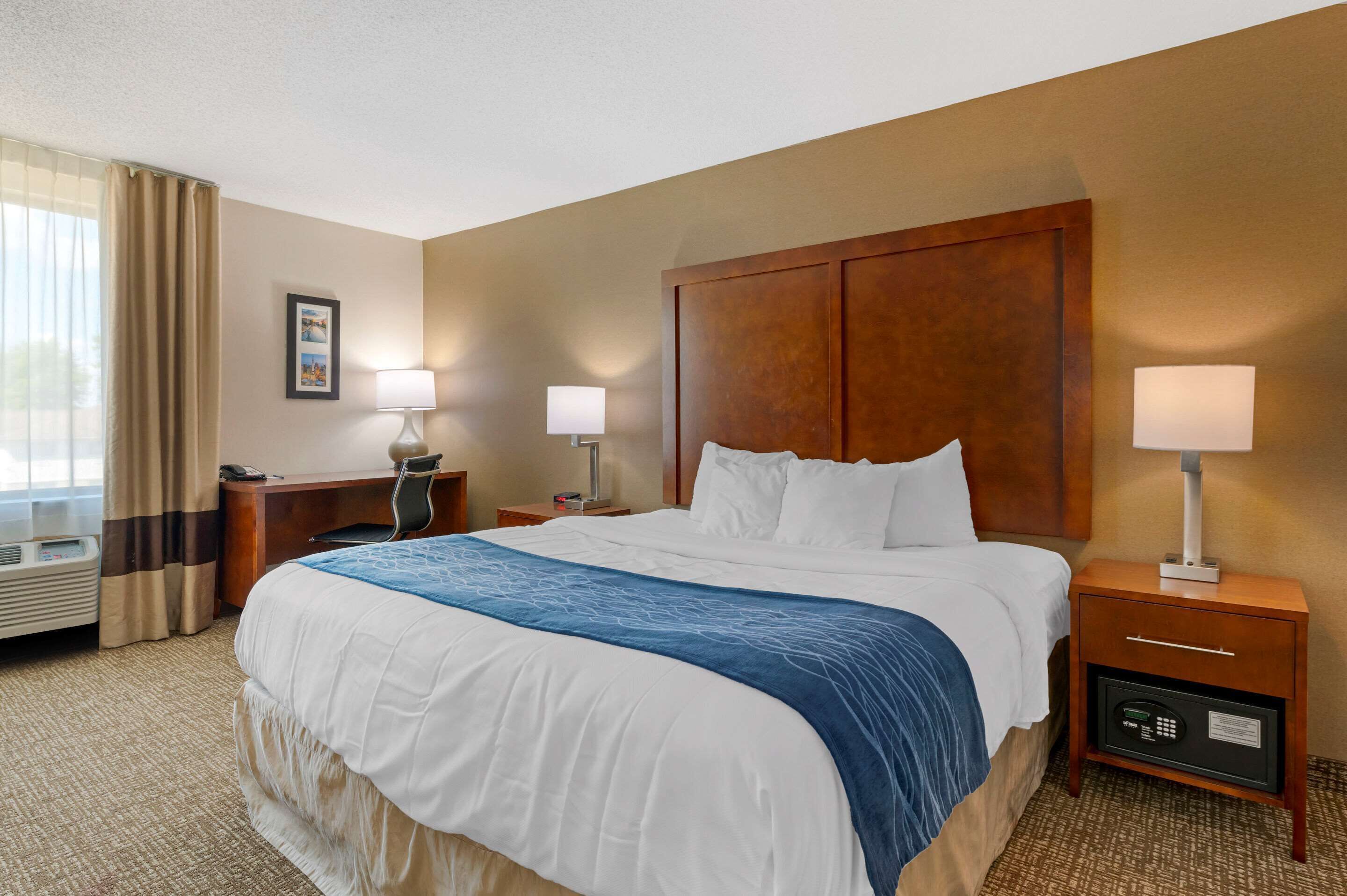 A hotel room with a large bed, two bedside tables, a desk, and a chair.