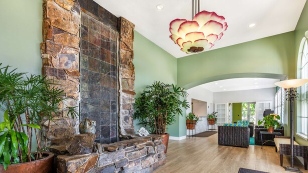 A spacious living area with a stone fireplace, green walls, and a large window. - Best Western Plus Capitola By-the-sea Inn & Suites (Santa Cruz)
