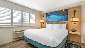 A hotel room with a large bed, a night sky mural, a wall-mounted heater, and a nightstand with a lamp. - Best Western Plus Capitola By-the-sea Inn & Suites (Santa Cruz)
