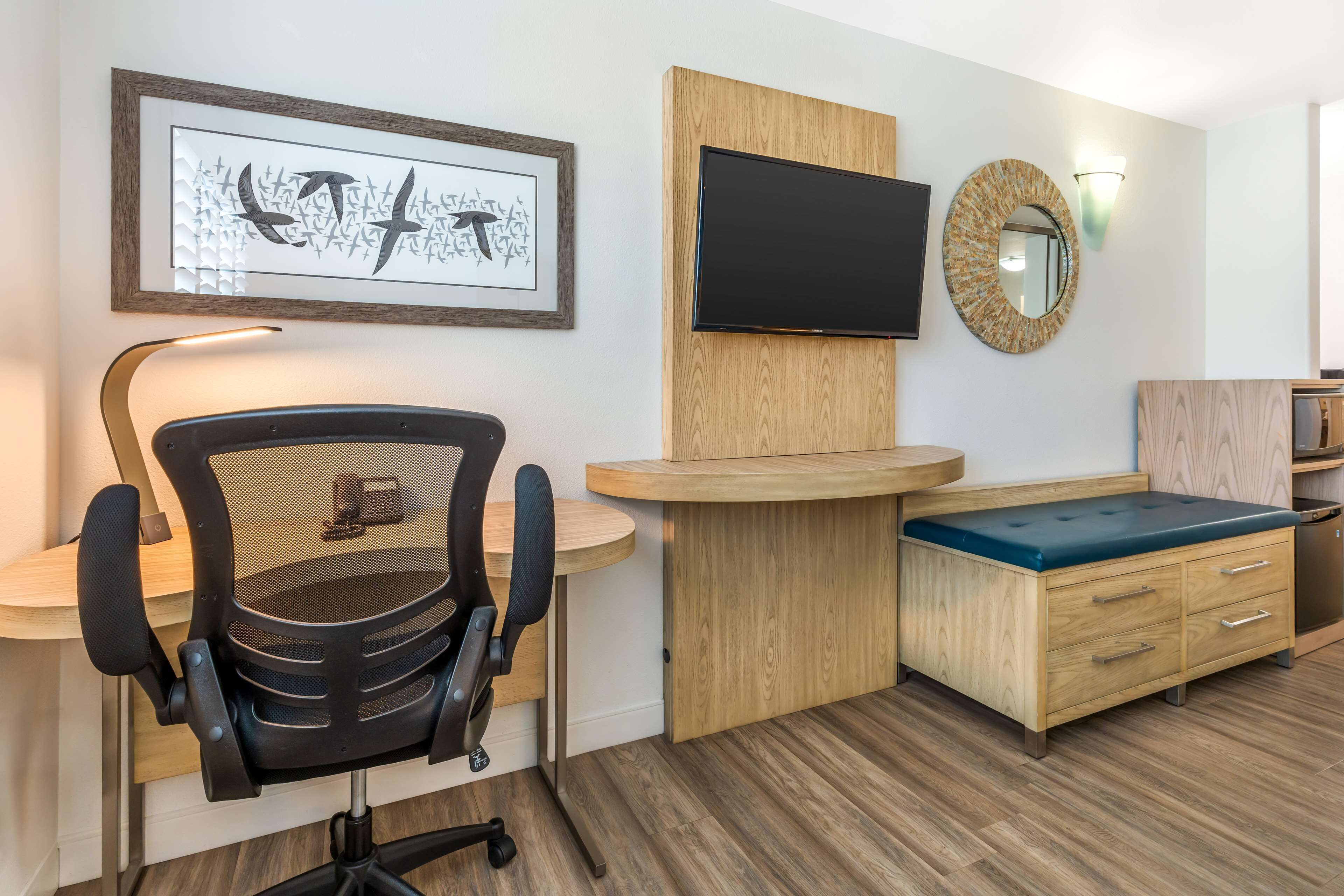 Una habitación moderna con escritorio, silla, televisión y un armario de madera.
