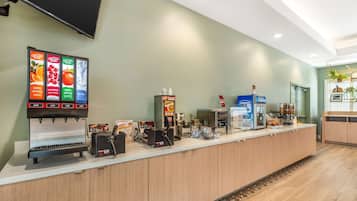 Una recepción moderna con una máquina de café, dispensador de agua y refrigerador Dannon.