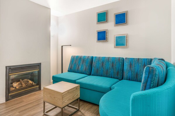 Un salon moderne avec un canapé de couleur turquoise, une petite table en bois et une cheminée.