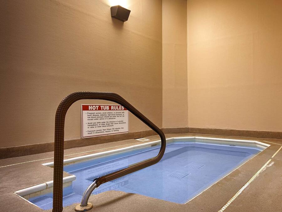 Un jacuzzi con un letrero de seguridad, un perchero y una zona junto a la piscina.