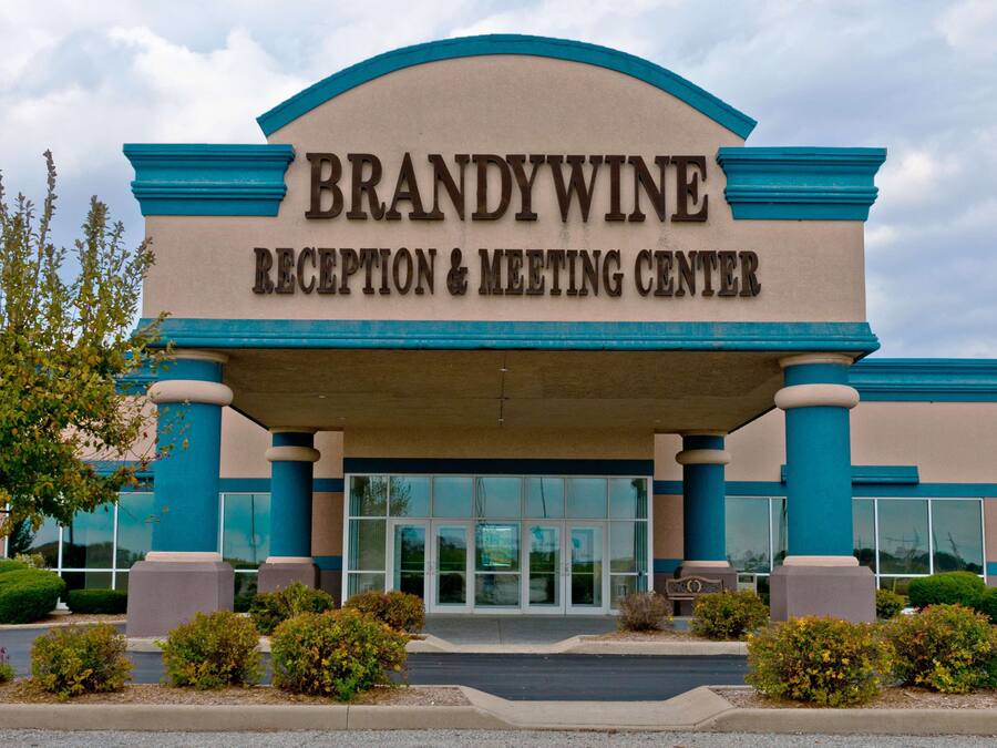 The exterior of the Brandywine Reception & Meeting Center with a clear entrance, large windows, and a landscaped area with shrubs.