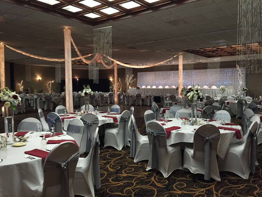 A banquet hall with round tables, grey chairs, and white tablecloths.