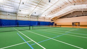 An indoor tennis court with a net, blue curtains, and a high ceiling with hanging lights. - Best Western Plus Brandywine Inn & Suites (Monticello)