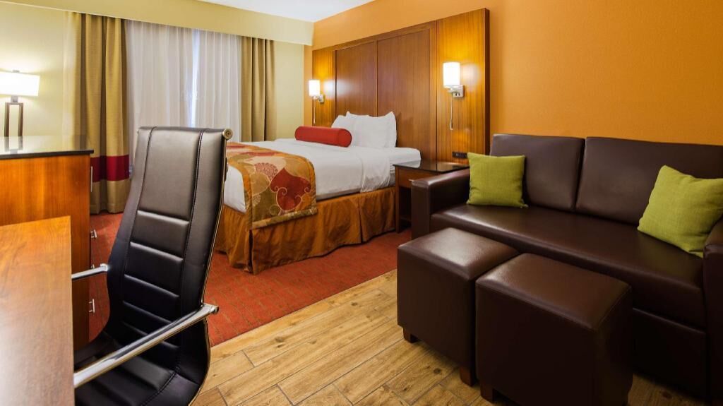Une chambre d’hôtel comprenant un lit, un bureau, une chaise, un canapé et une petite table.