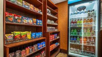 A snack and beverage vending area with various snack brands and a refrigerated drink dispenser.