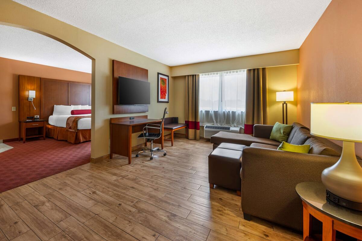 Habitación de hotel con cama, escritorio, silla, sofá y televisor.