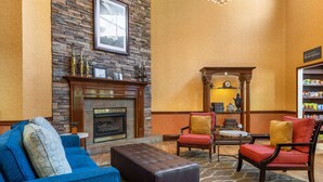 A lobby with a stone fireplace, blue and red chairs, a blue sofa, and a wooden coffee table. - Best Western Plus Georgetown Corporate Center Hotel (Georgetown)