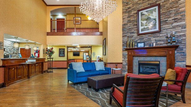 A spacious lobby with a wooden reception desk, a blue sofa, a fireplace, and a chandelier. - Best Western Plus Georgetown Corporate Center Hotel (Georgetown)