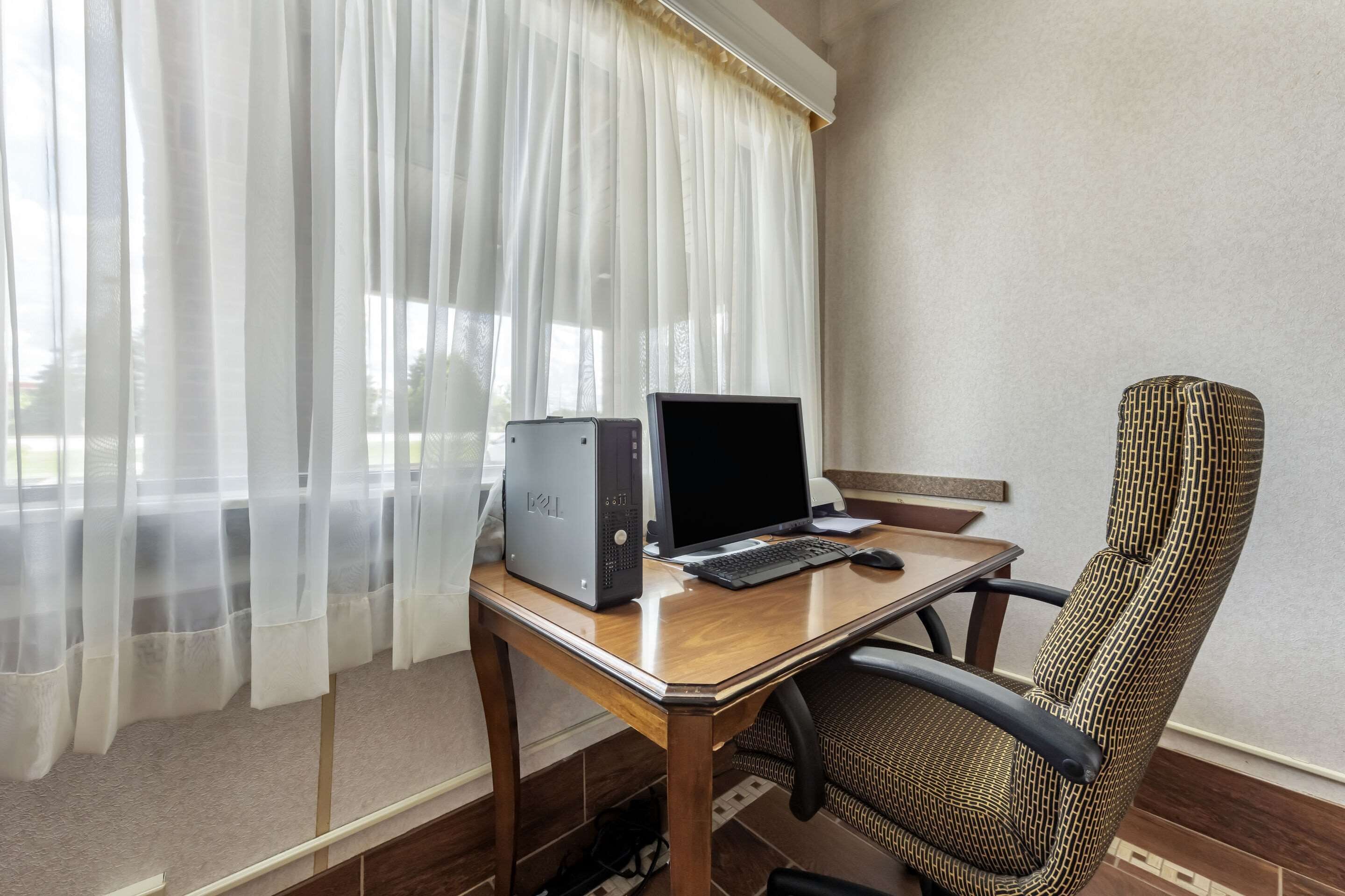 A room with a desk, a computer, and a chair.