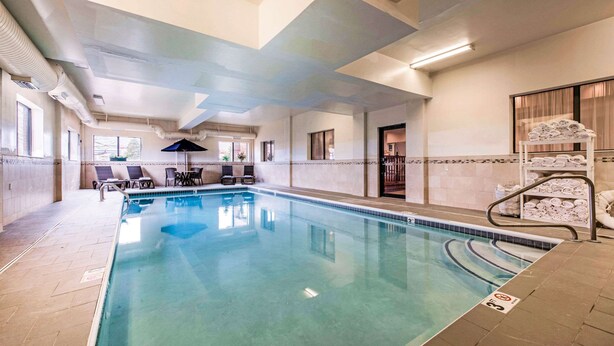 An indoor swimming pool with lounge chairs and a towel rack. - Comfort Inn & Suites Streetsboro - Kent (Streetsboro)