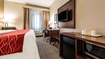 A hotel room with a bed, desk, television, and microwave.