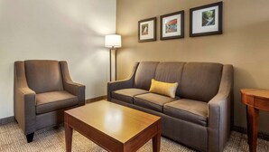A hotel room with a sofa, armchair, and a small table. There are three framed pictures on the wall. - Comfort Inn & Suites Streetsboro - Kent (Streetsboro)