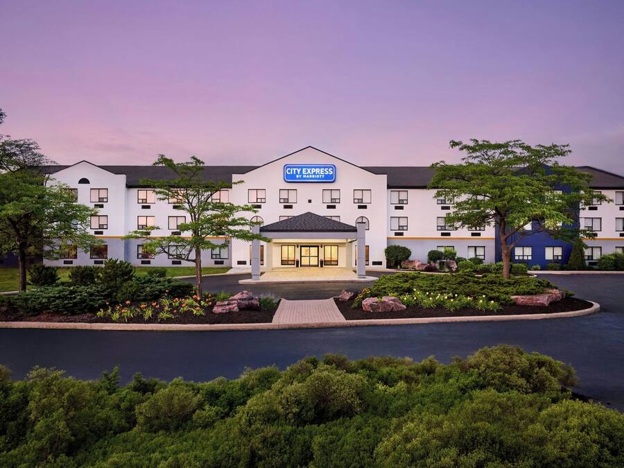 Ein Hotel mit einem zentralen Eingang, mehreren Etagen und einem angelegten Vorgarten.