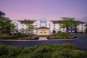 A hotel with a central entrance, multiple floors, and a landscaped front yard.