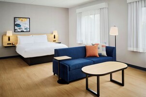 Una habitación de hotel con una cama, un sofá, una mesita y una lámpara.
