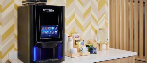 Una cafetera con pantalla digital sobre una encimera, rodeada de tazas y recipientes para café.
