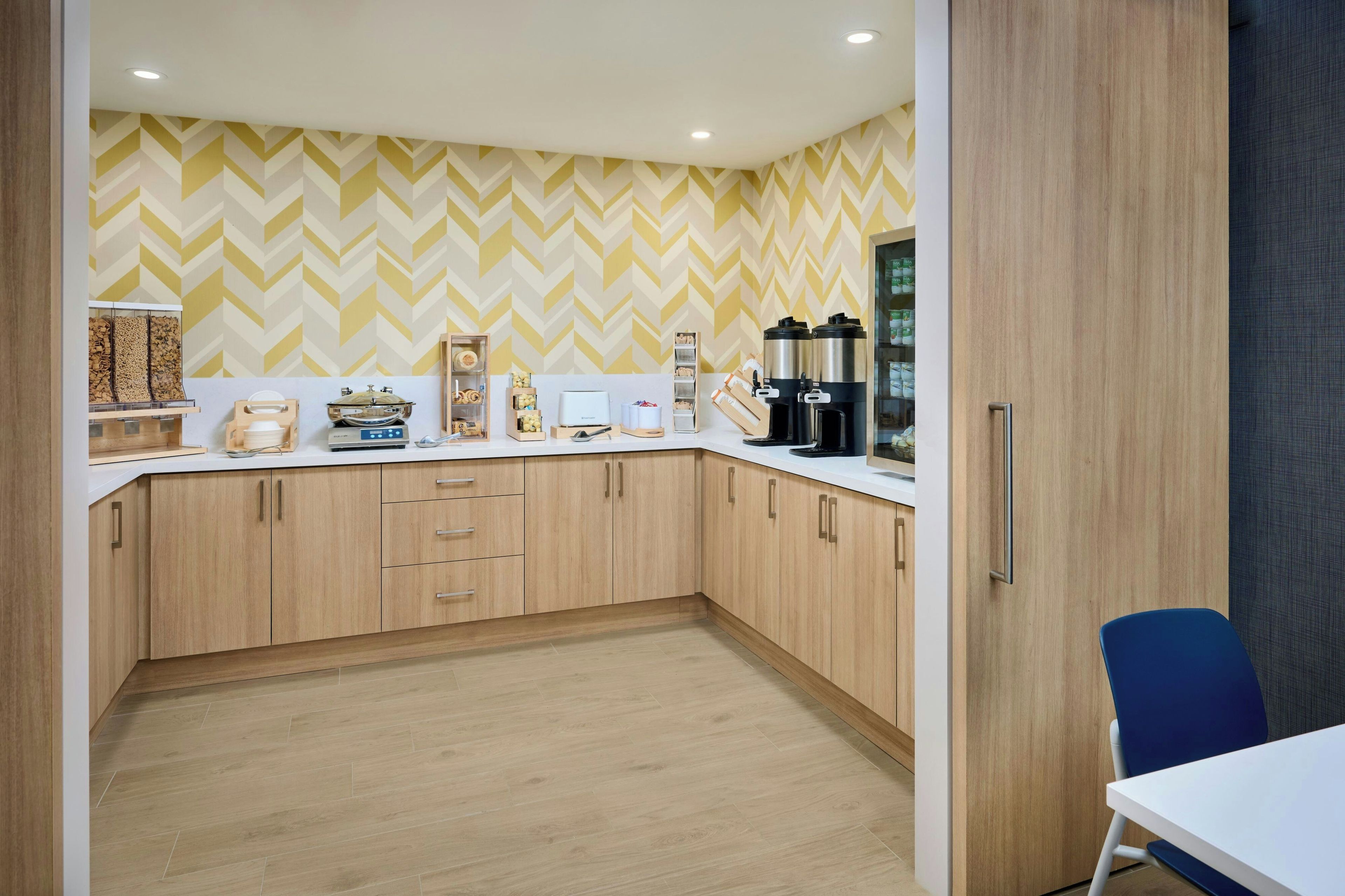 Una cocina moderna con armarios de madera, encimera blanca y salpicadero con motivo de espiga.