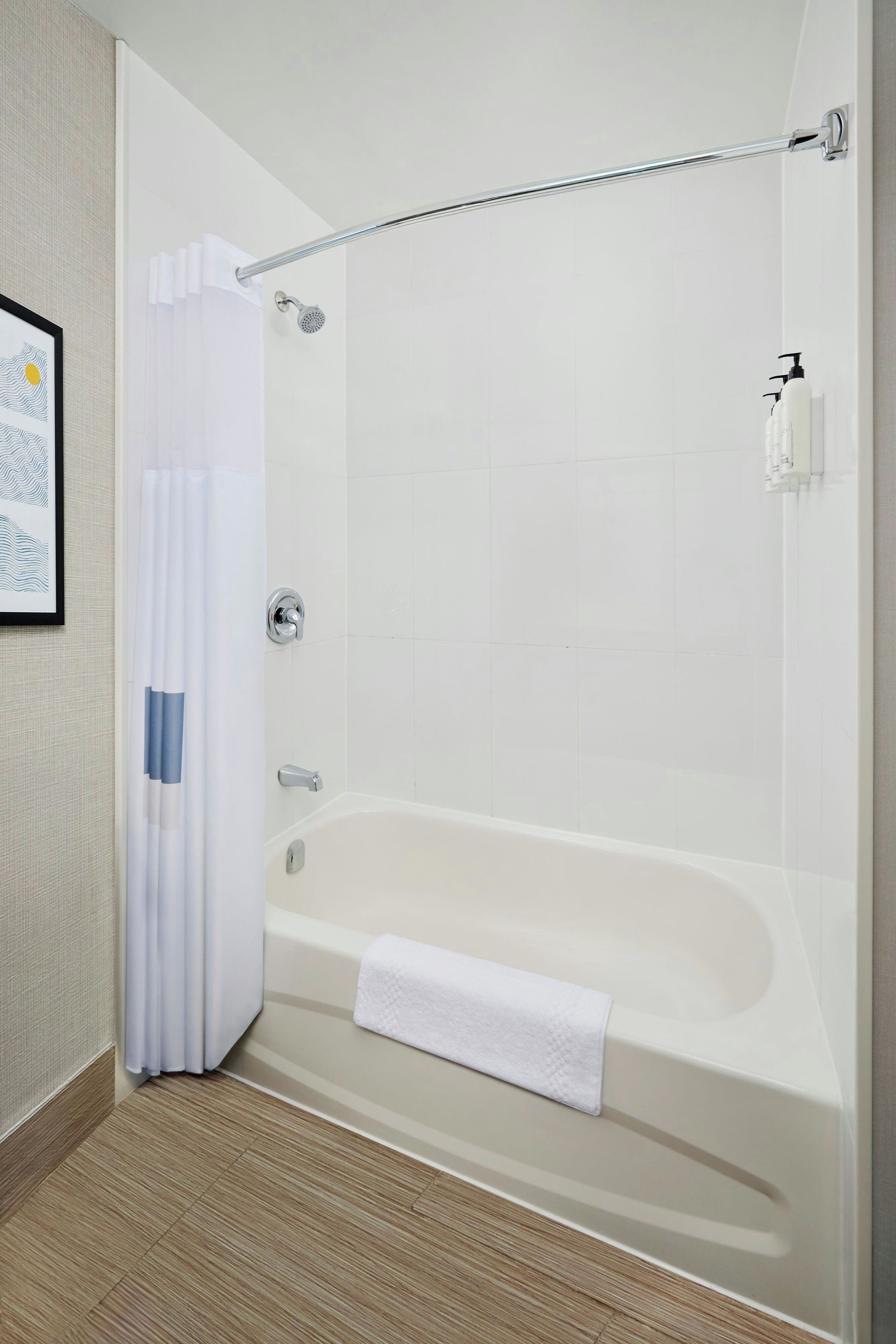 Un baño moderno con bañera, ducha y barras de apoyo.