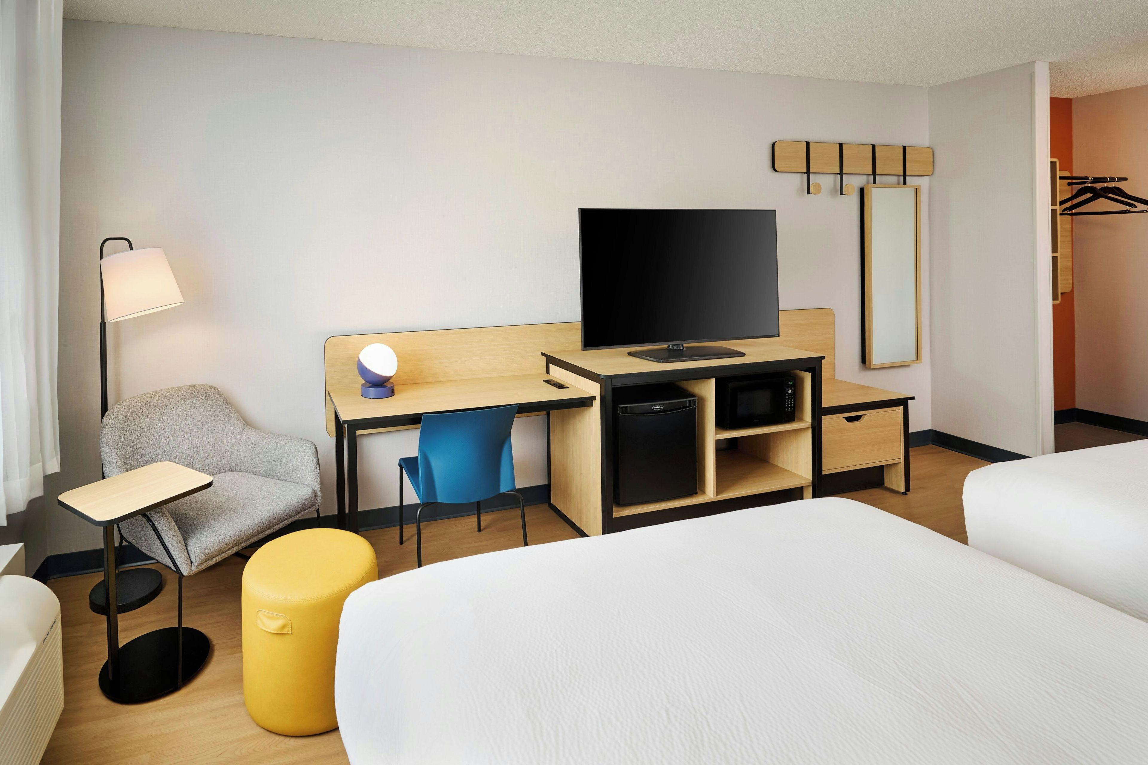 Ein Hotelzimmer mit Bett, Schreibtisch, Fernseher, Sessel und einem kleinen Stauraum.