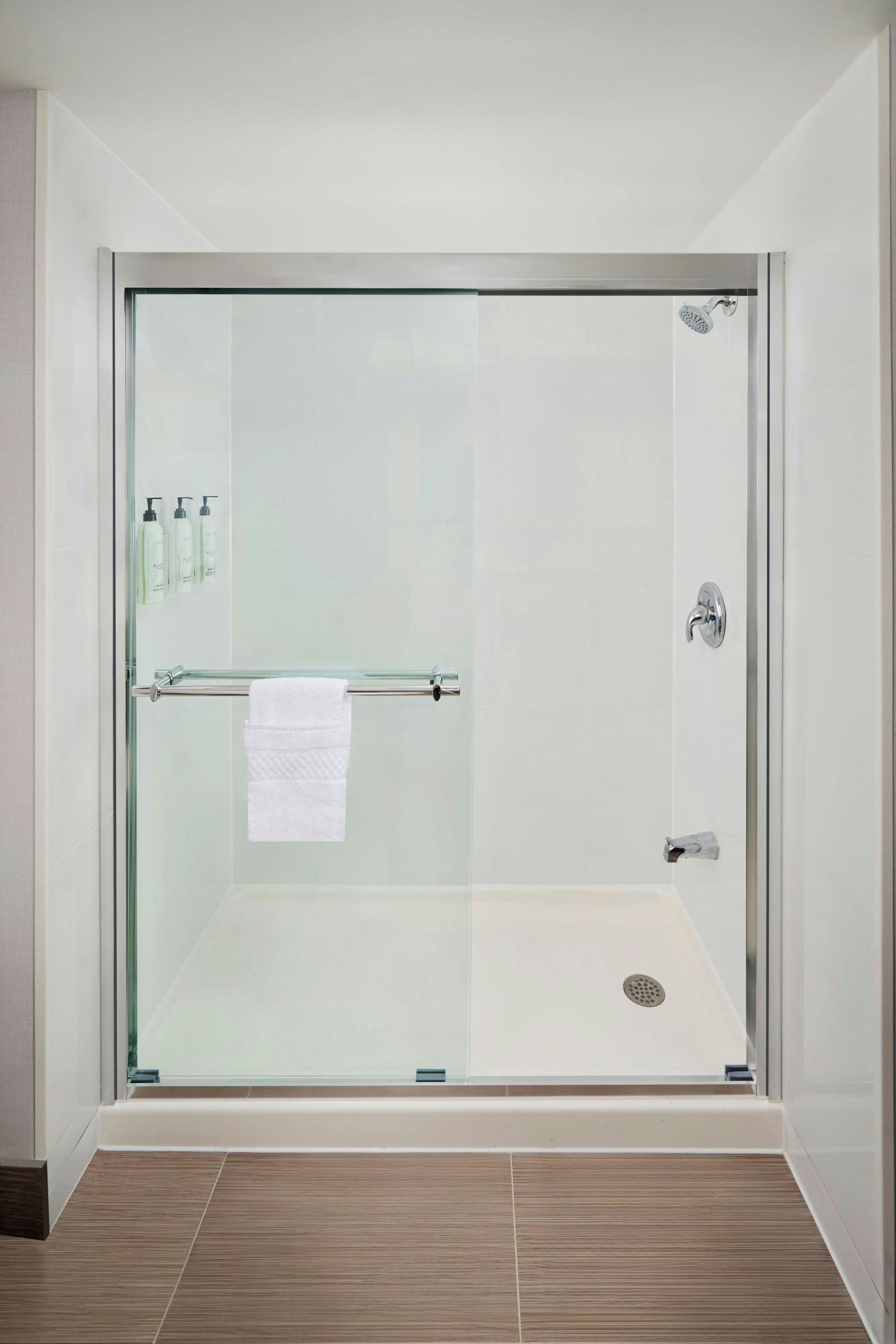 A modern shower with a glass door, a towel rack, and a showerhead.