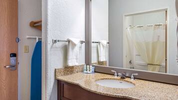 A bathroom with a granite countertop sink, a large mirror, a towel rack, and a shower curtain.