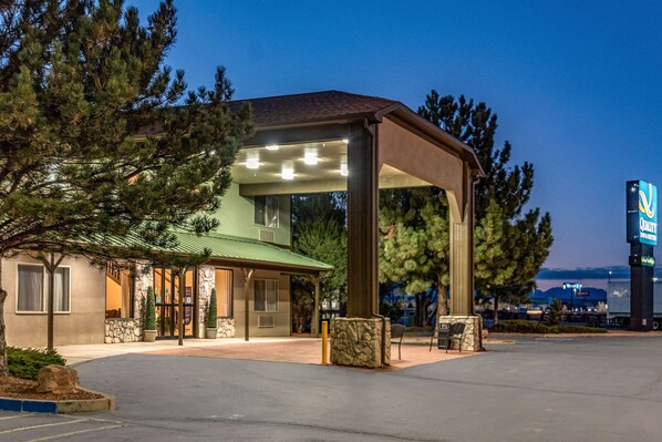 A hotel with a covered entrance, outdoor seating, and a parking lot.