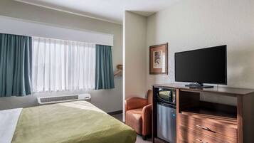 Una habitación de hotel con cama, escritorio, televisor y una silla.