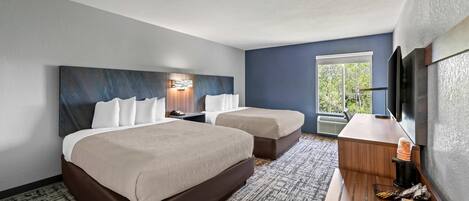 Una habitación de hotel con dos camas, un escritorio, una cafetera y un televisor.