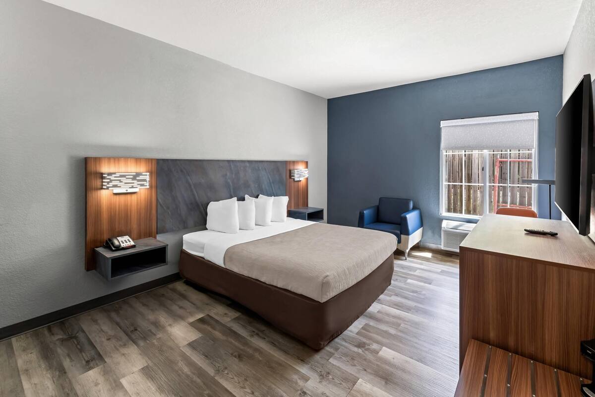 A modern hotel room with a large bed, bedside tables, a desk, and a chair.