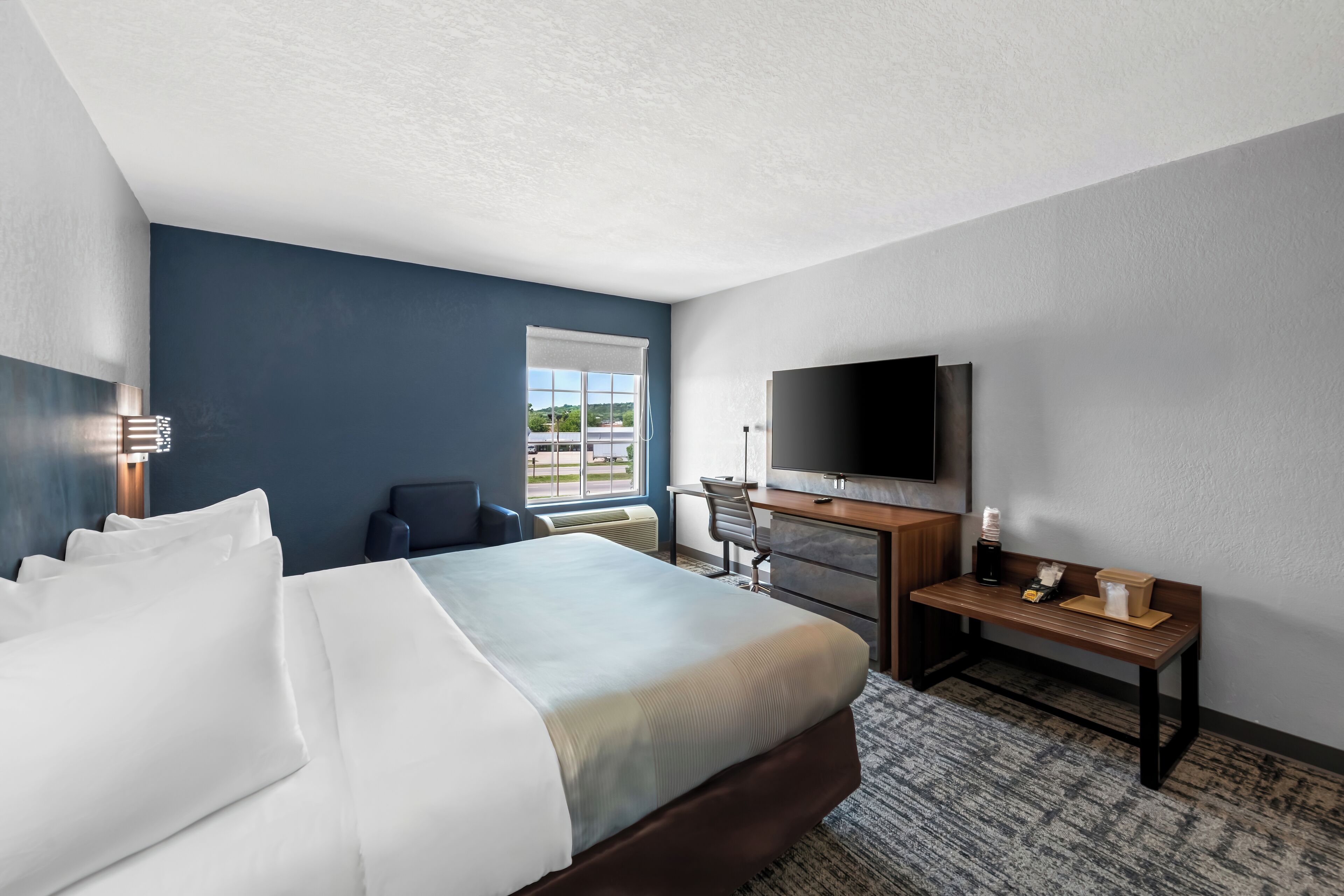 Hotelkamer met een bed, een bureau, een stoel, een televisie en een raam met uitzicht.