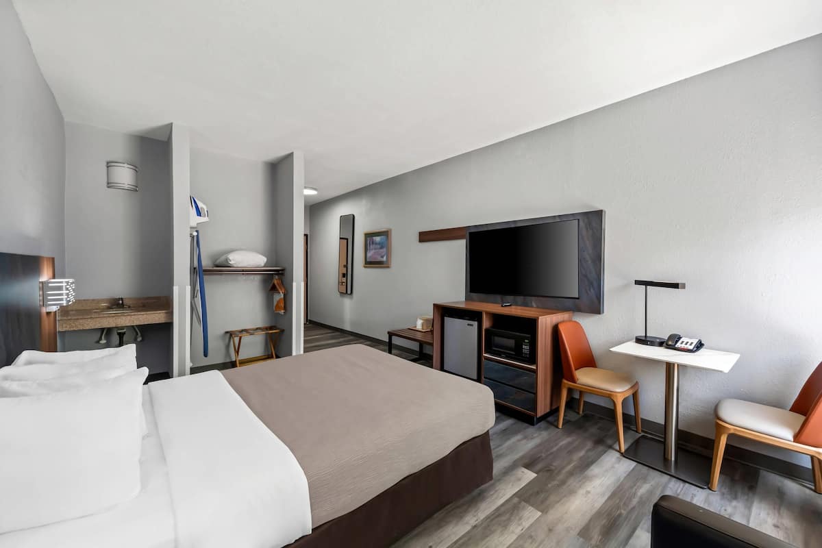 Ein Hotelzimmer mit Bett, Schreibtisch, Fernseher, Mikrowelle und einer Sitzecke.