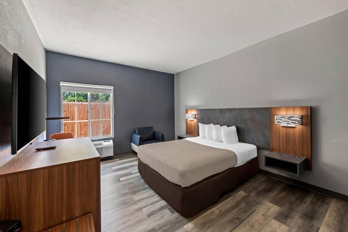 Una habitación de hotel moderna con una cama grande, un escritorio, una silla y un televisor.