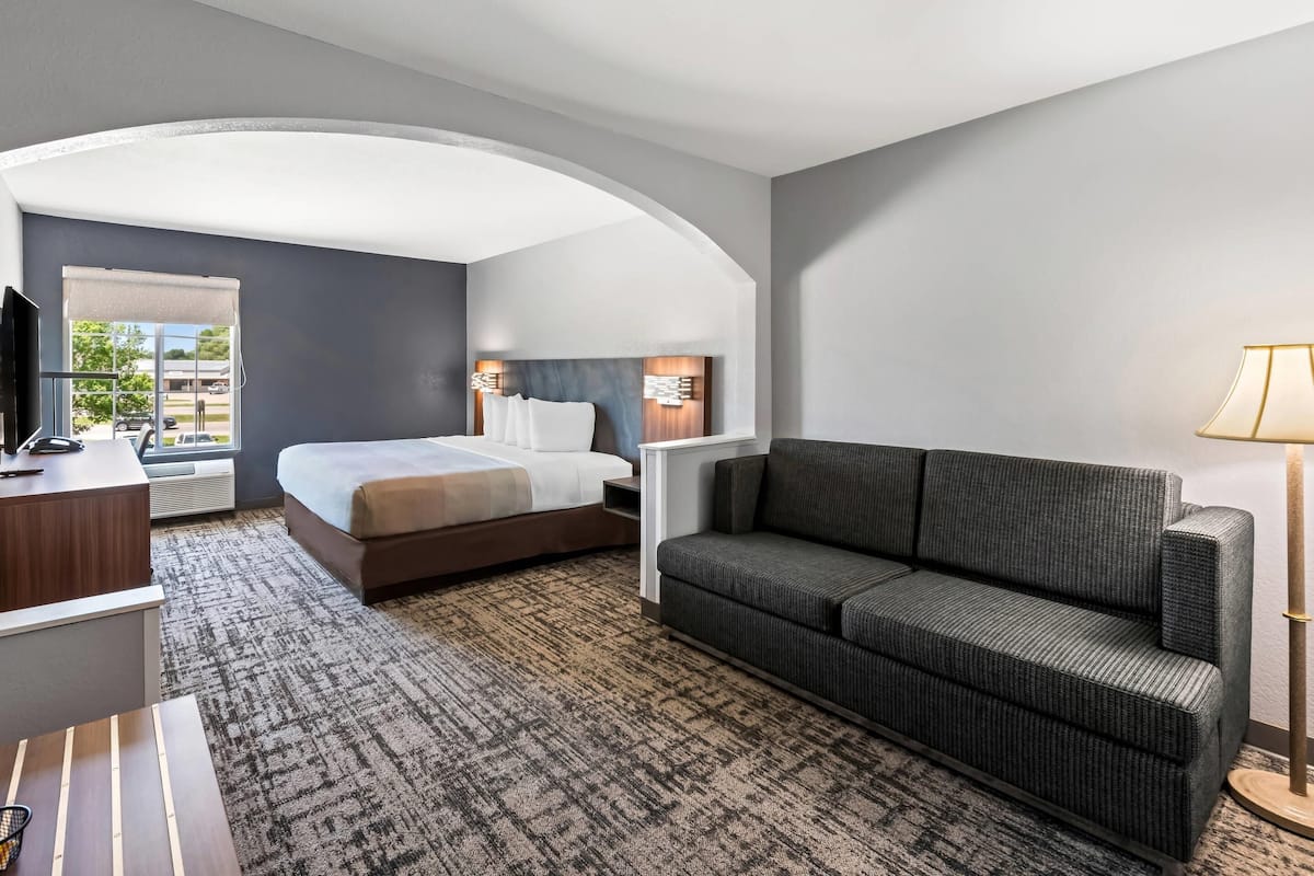 Ein Hotelzimmer mit Bett, Sofa, Schreibtisch und Fernseher.